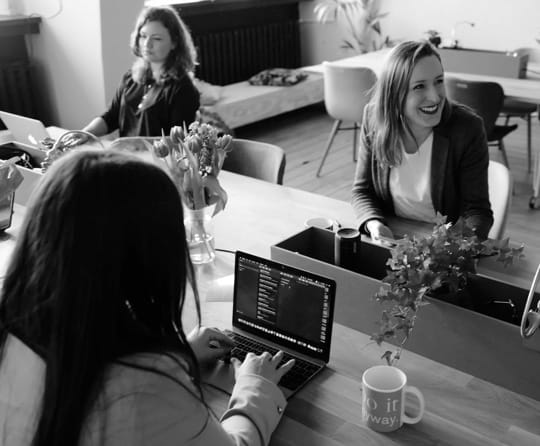 Three ladies siting into office and joking.