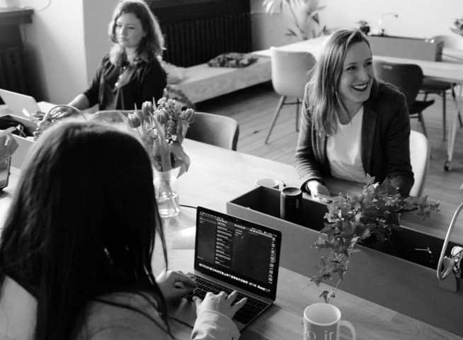 Three ladies siting into office and joking.